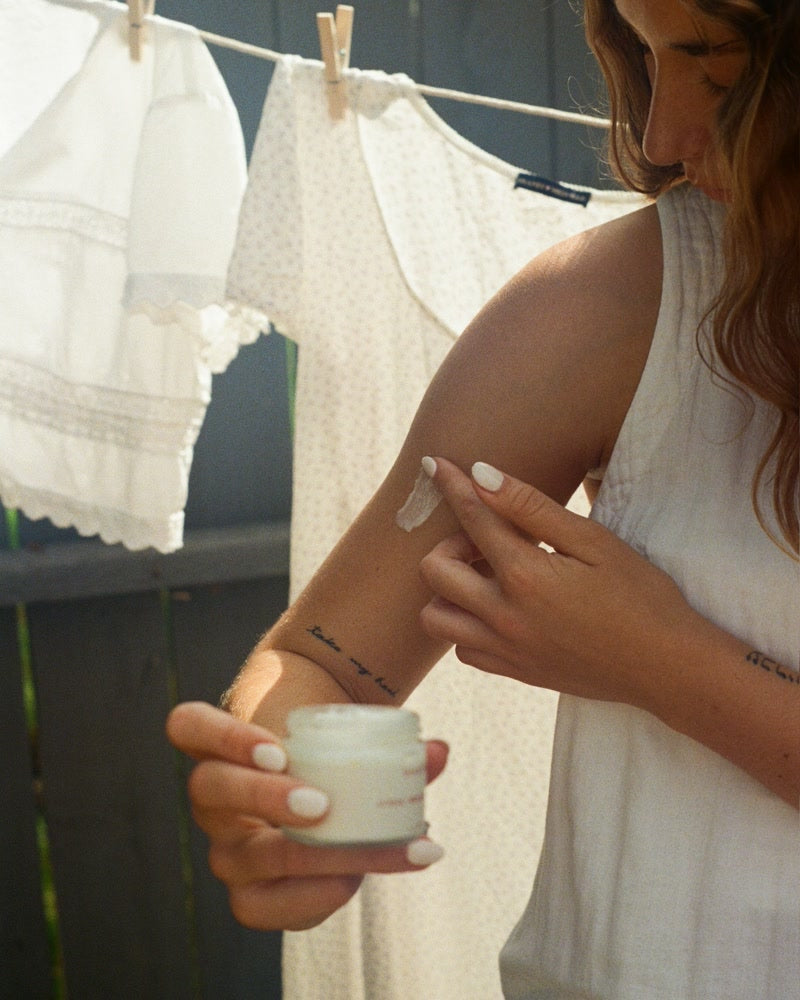 A woman applying one of the Synced Skin balms to her arm