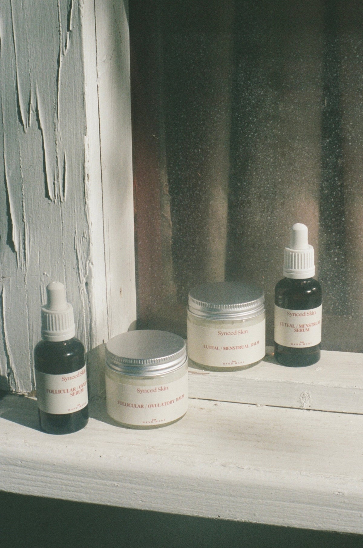 Synced Skin serums and balms beside a window