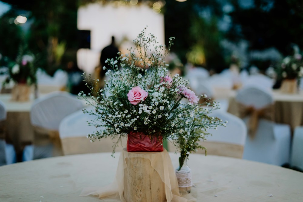 Pink roses and delicate white flowers on a celebration table.