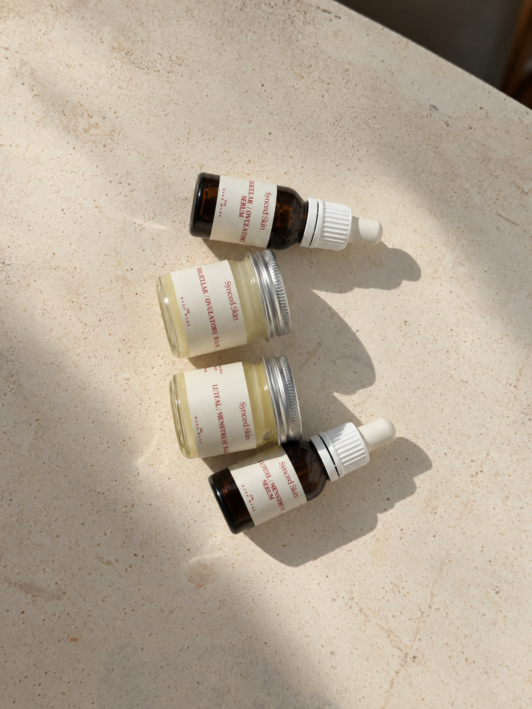 Mini Synced Skin Starter Kit photographed on stone: two serums and two balms.